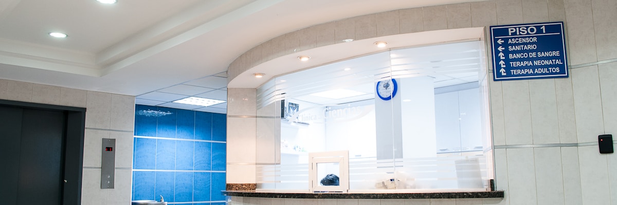 Bright modern hospital corridor with white walls, clean floors and directional signage